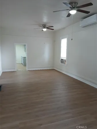 an empty room with wooden floor fan and windows