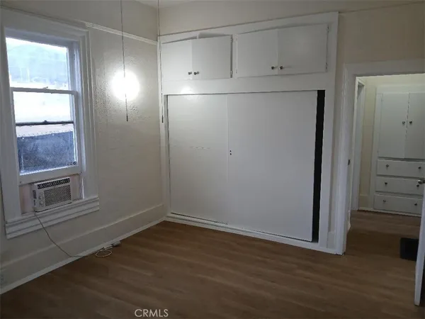 an empty room with wooden floor cabinet and window