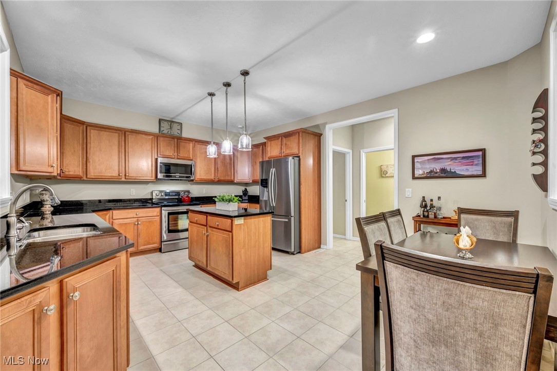 30257 Center Ridge Road Westlake, OH 44145 - Photo 11 of 42 Kitchen with brown cabinets, stainless steel appliances, a kitchen island, hanging light fixtures, and dark stone countertops