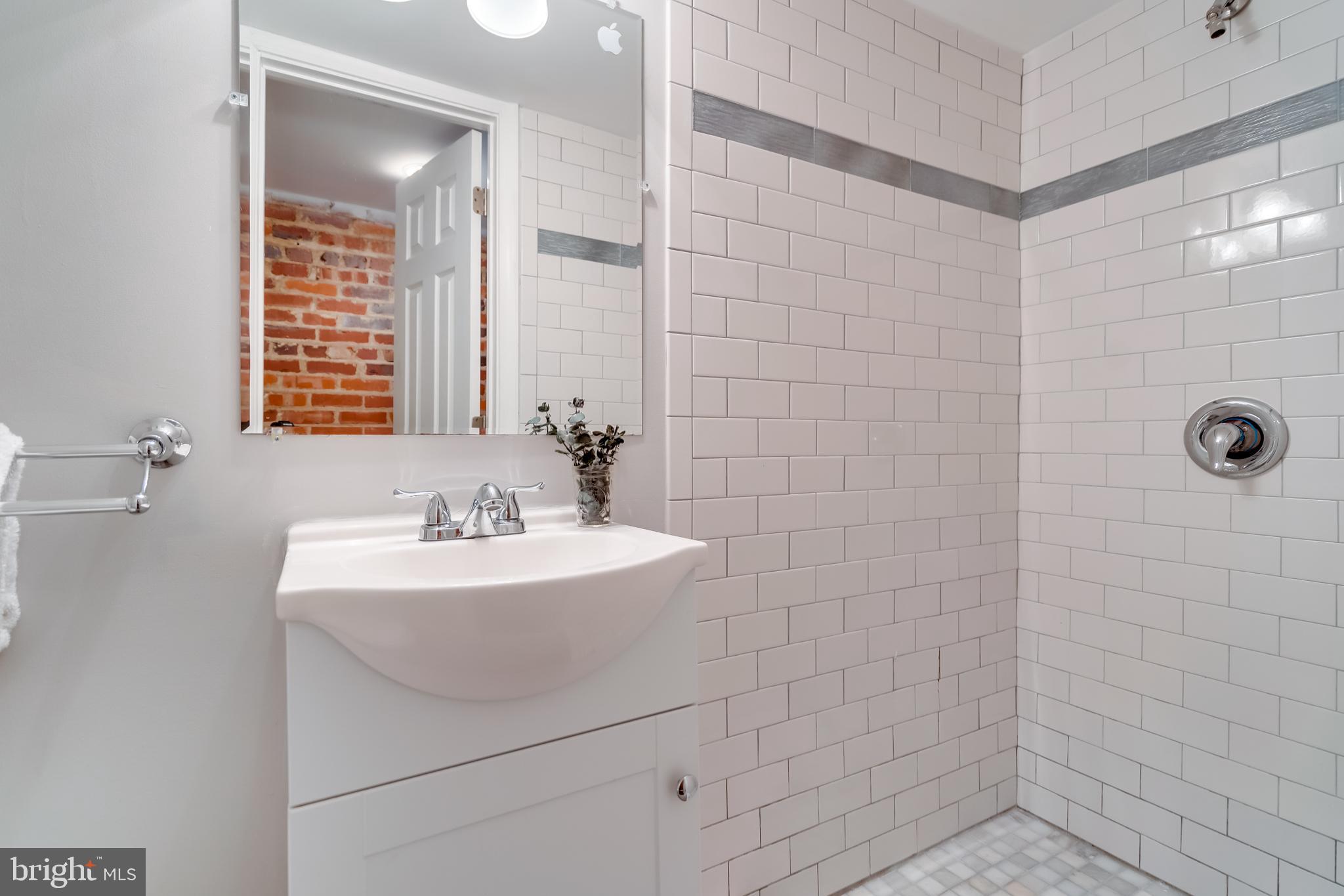 2211 38th Street Northwest Washington, DC 20007 - Photo 36 of 51 a bathroom with a sink a shower and a mirror