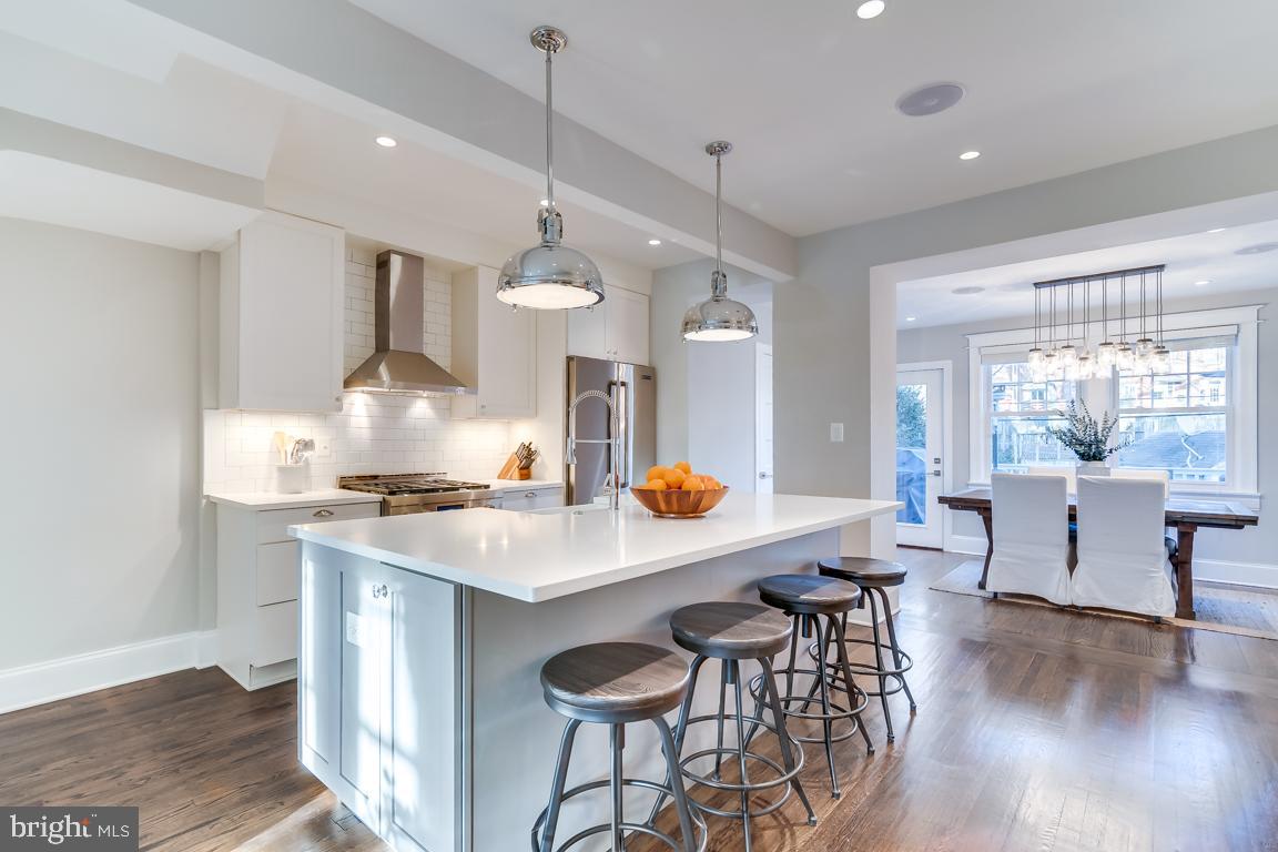 2211 38th Street Northwest Washington, DC 20007 - Photo 7 of 51 a kitchen with stainless steel appliances a table chairs refrigerator and wooden floor