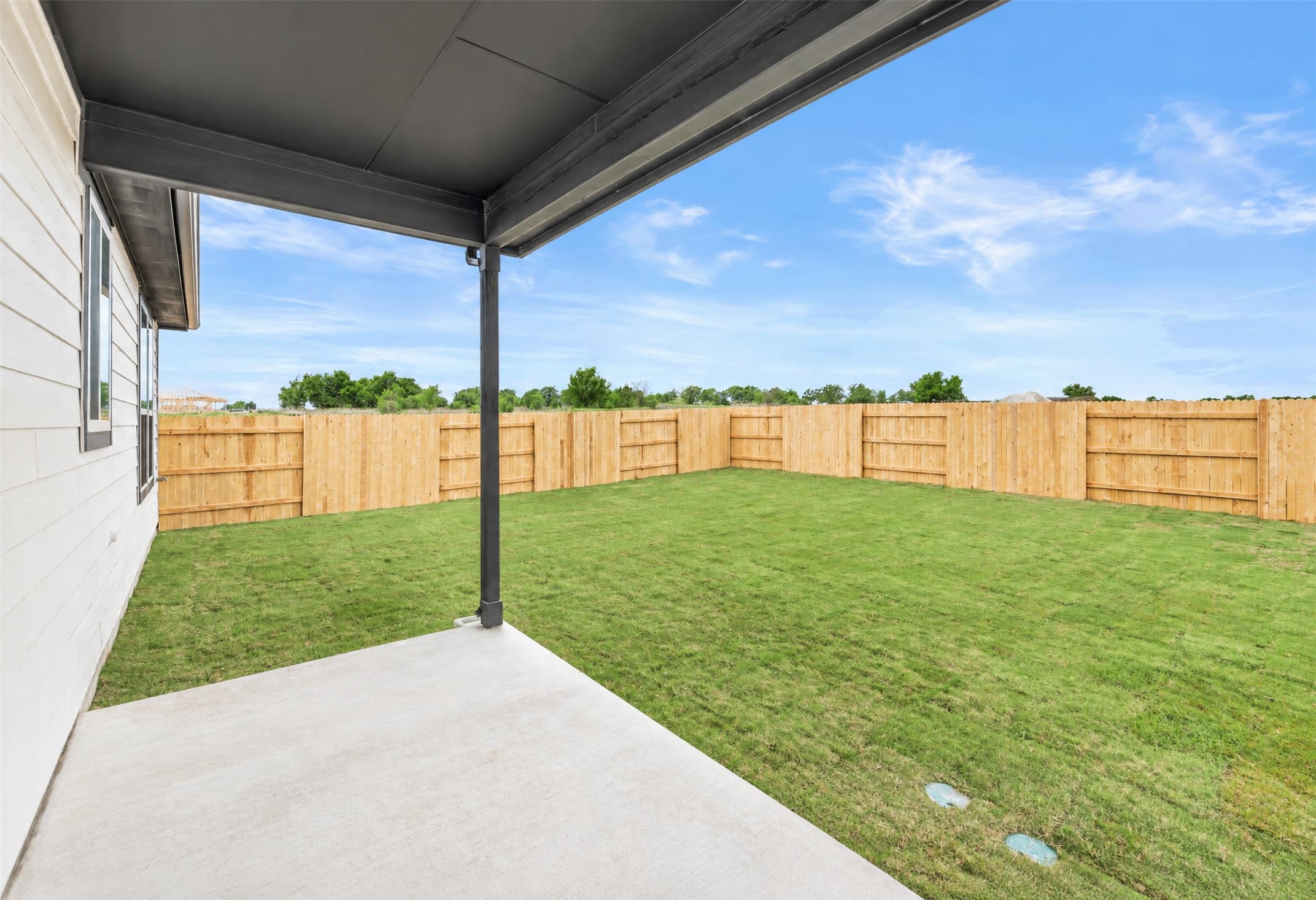 545 Henry Milton Road Georgetown, TX 78626 - Photo 12 of 33 A covered concrete patio overlooks the spacious grassy yard enclosed by wooden fencing.