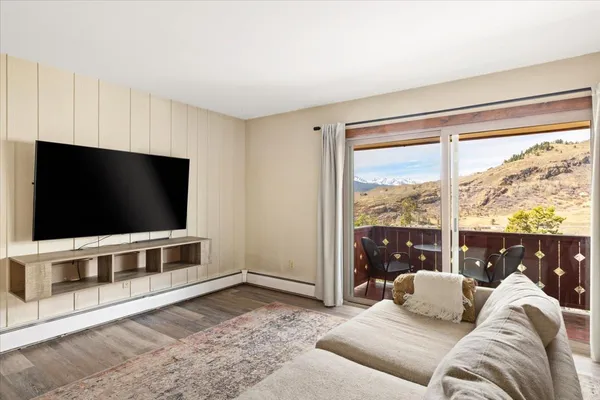 a living room with furniture a flat screen tv and a floor to ceiling window