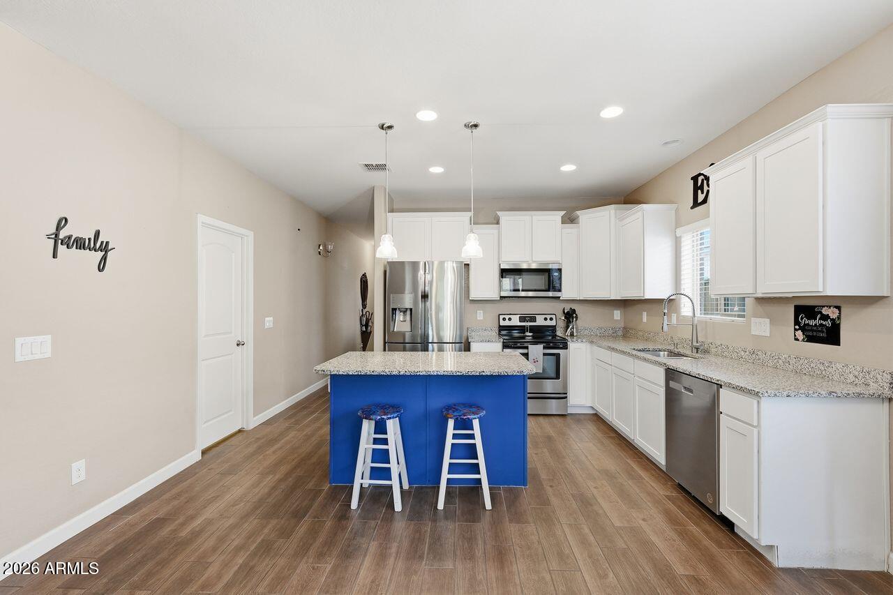 23602 West Ripple Road Buckeye, AZ 85326 - Photo 12 of 38 a kitchen with stainless steel appliances granite countertop a table chairs sink refrigerator and cabinets