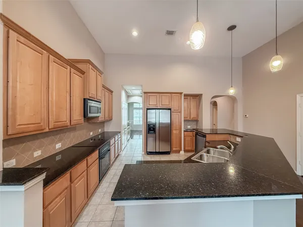 a kitchen with kitchen island granite countertop a sink a counter top space appliances and cabinets