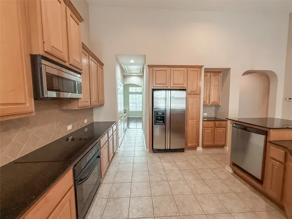 a kitchen with stainless steel appliances granite countertop a refrigerator a stove a sink and a microwave