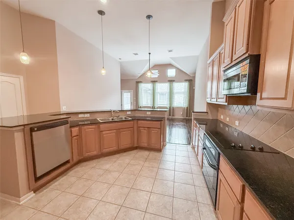 a large kitchen with granite countertop a stove a sink and a refrigerator