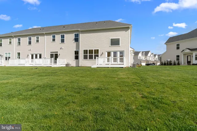 a view of a white house with a big yard and large trees