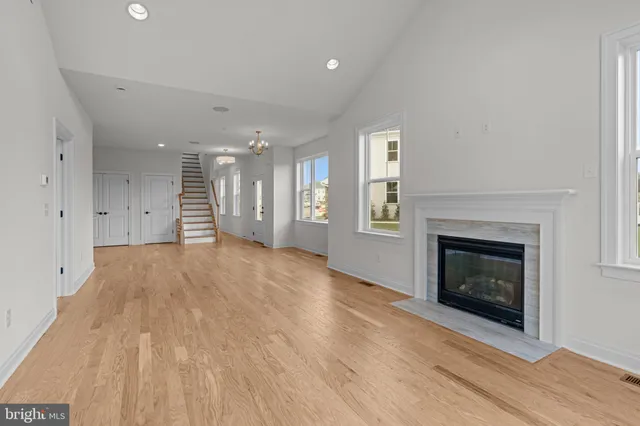 a view of an empty room with wooden floor fireplace and a window