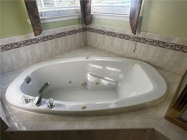 a bathroom with a tub a sink a mirror and a shower
