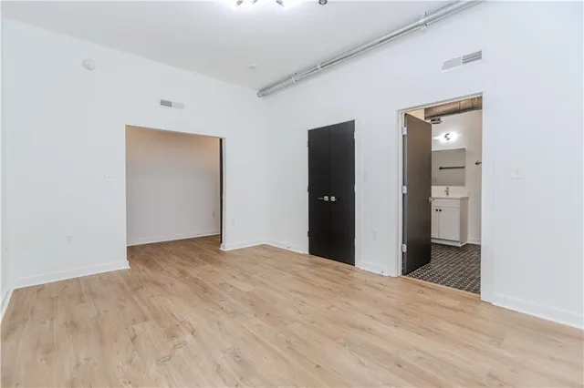 a view of an empty room with wooden floor and closet