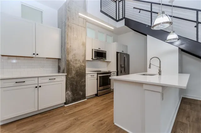 a kitchen with cabinets stainless steel appliances and wooden floor