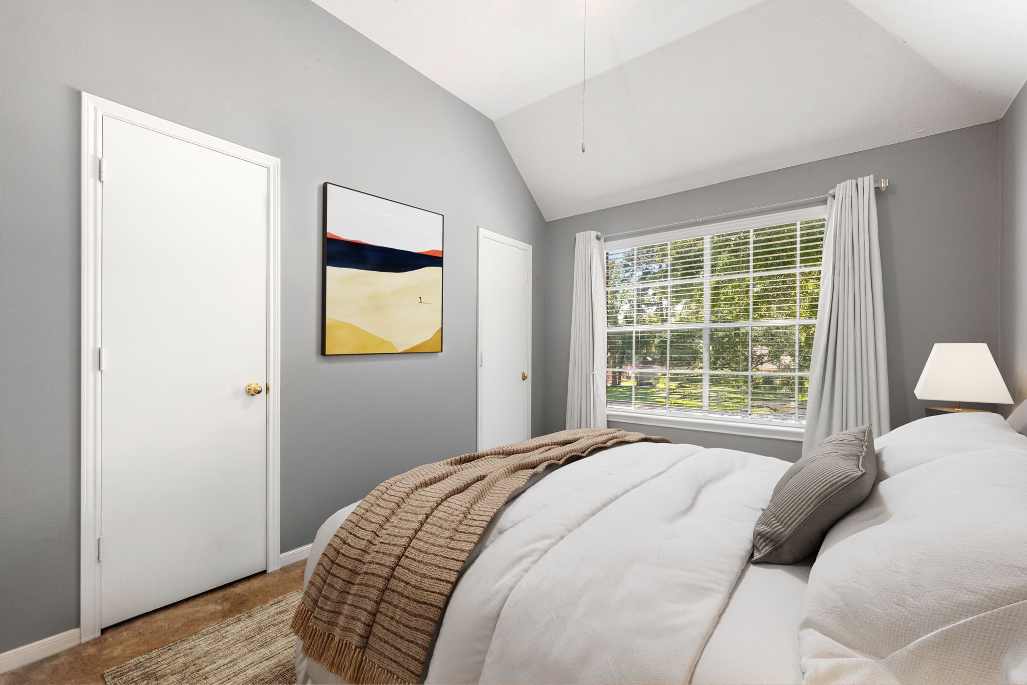 19726 Teller Boulevard Spring, TX 77388 - Photo 16 of 24 This cozy secondary bedroom offers a restful escape with its modern grey walls and vaulted ceiling. A large window provides plenty of natural light and views of the surrounding greenery, while the wood-look flooring adds a touch of warmth. With its clean lines and quiet atmosphere, this room is perfect for guests or family members to relax in style.