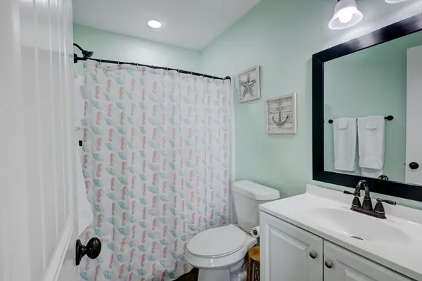 a bathroom with a sink a toilet a mirror and shower curtain