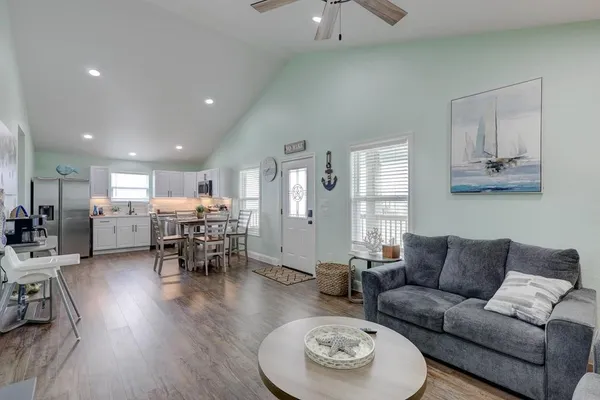 a living room with furniture kitchen view and a wooden floor