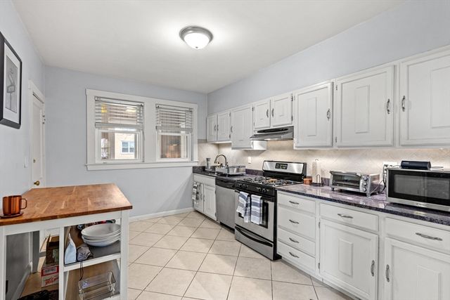 a kitchen with stainless steel appliances granite countertop a stove a sink and white cabinets