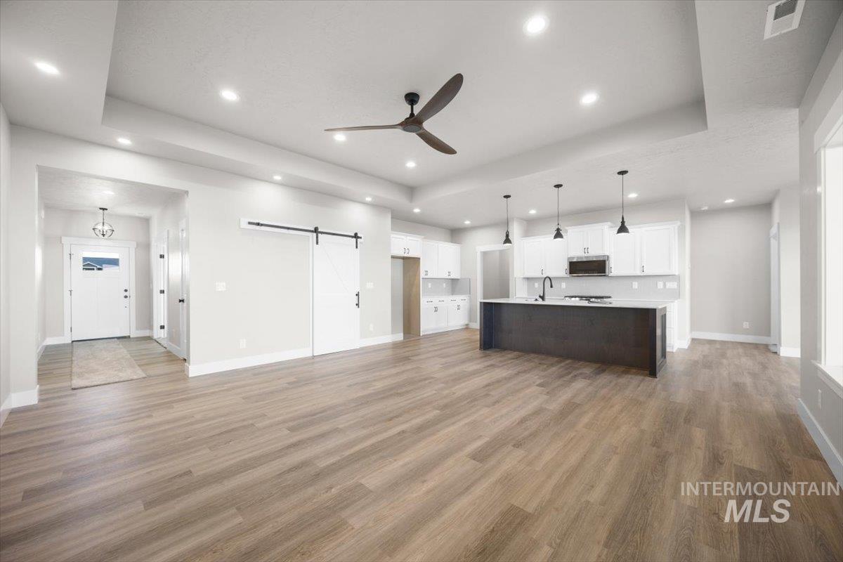 103 Ash Street Parma, ID 83660 - Photo 21 of 22 Kitchen featuring a barn door, a raised ceiling, a ceiling fan, open floor plan, and light countertops