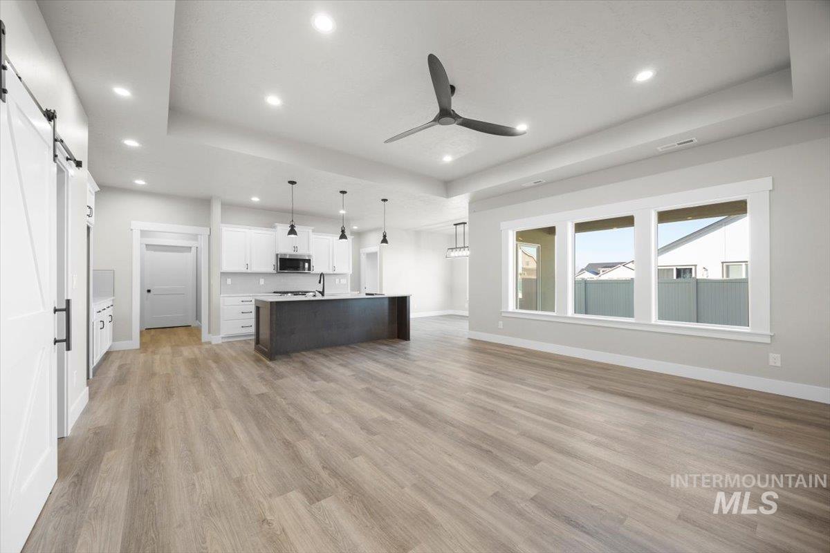 103 Ash Street Parma, ID 83660 - Photo 22 of 22 Kitchen with open floor plan, a barn door, a tray ceiling, light countertops, and a kitchen island with sink