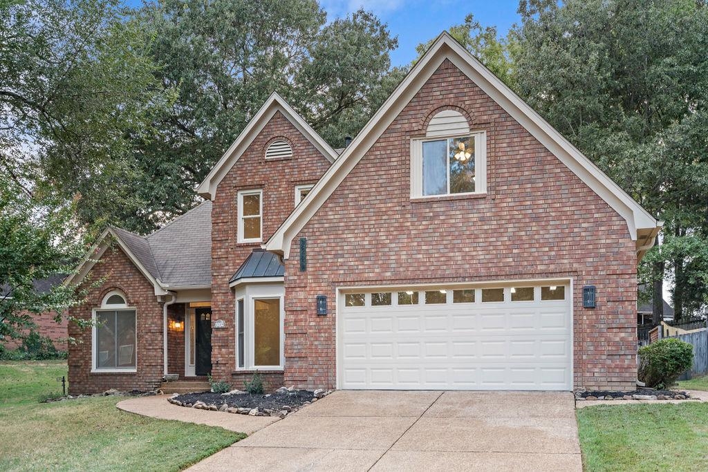 View of front of house with a front lawn, brick siding, and driveway