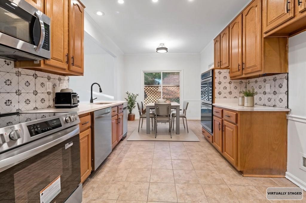 2389 Carrol Ridge Lane Cordova, TN 38016 - Photo 7 of 18 Kitchen with tasteful backsplash, appliances with stainless steel finishes, brown cabinets, recessed lighting, and crown molding