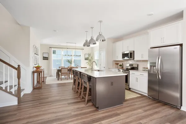 a kitchen with stainless steel appliances a refrigerator a stove a sink dishwasher with a dining table and chairs with wooden floor