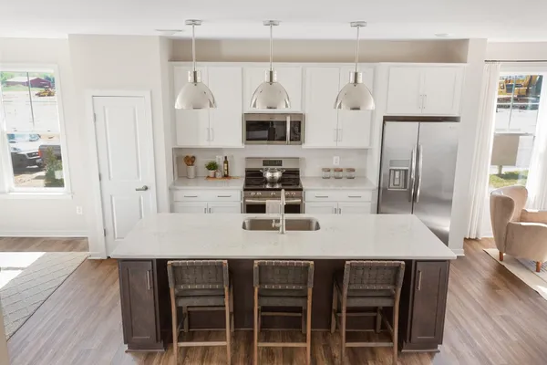 a kitchen with stainless steel appliances granite countertop a stove a refrigerator a oven a white table and chairs with wooden floor