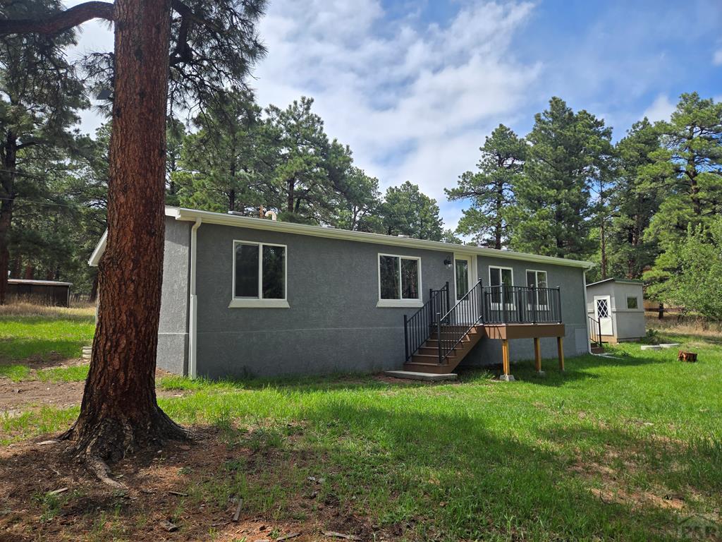 a backyard of a house with wooden fence and large trees