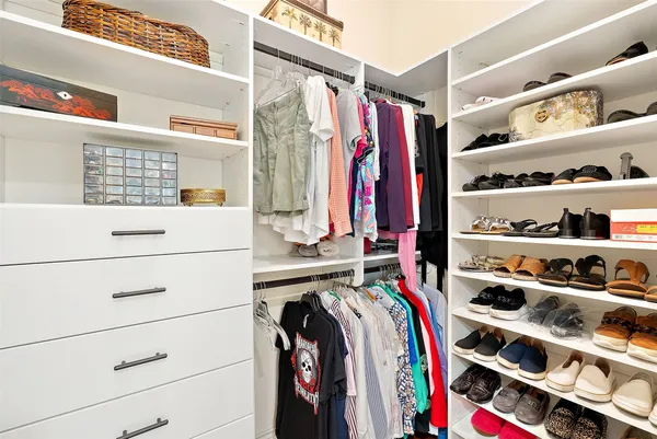 a view of walk in closet with clothes and shoes