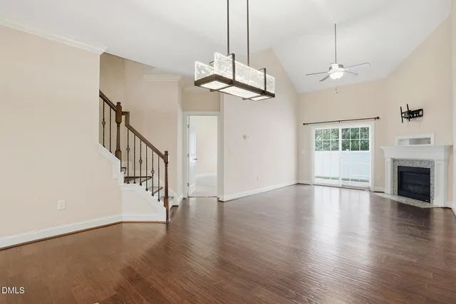 a view of an empty room with wooden floor fireplace and a window