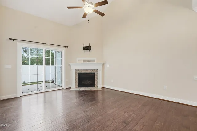 an empty room with windows fireplace and wooden floor