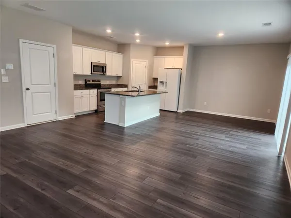 a kitchen with stainless steel appliances granite countertop a refrigerator stove top oven and cabinets with wooden floor