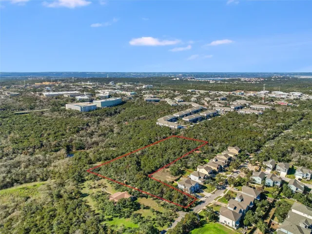 an aerial view of residential houses with outdoor space and trees