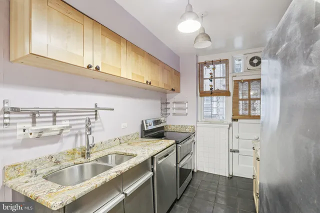 a kitchen with stainless steel appliances granite countertop a sink and dishwasher a refrigerator with wooden cabinets