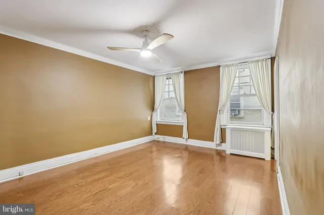 an empty room with wooden floor cabinet and windows