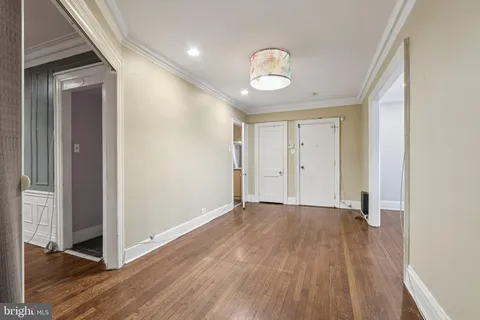 a view of an empty room with wooden floor and closet