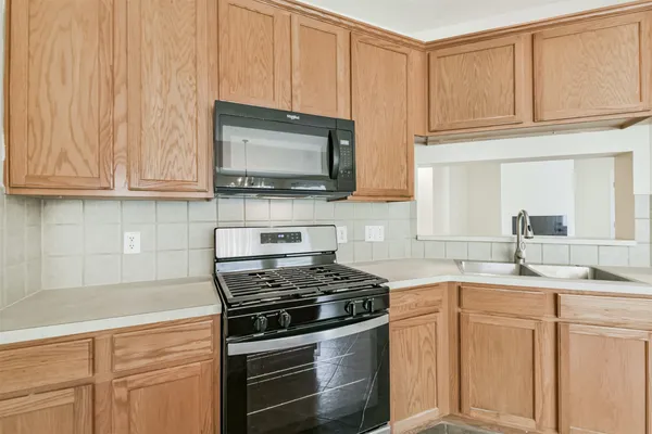 a kitchen with stainless steel appliances granite countertop a stove top oven a sink a refrigerator and white cabinets