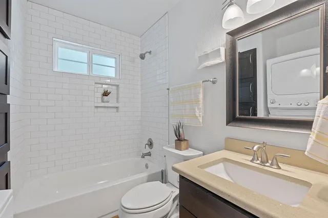 a bathroom with a granite countertop sink toilet a mirror and bathtub