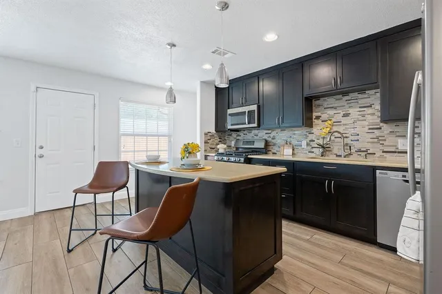 a kitchen with stainless steel appliances kitchen island granite countertop a table chairs sink and cabinets