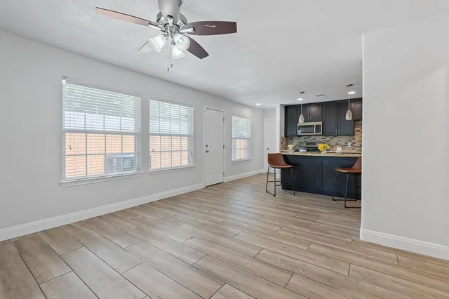a view of an empty room with a window and wooden floor