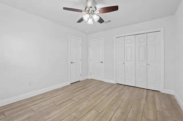 a view of an empty room with chandelier fan