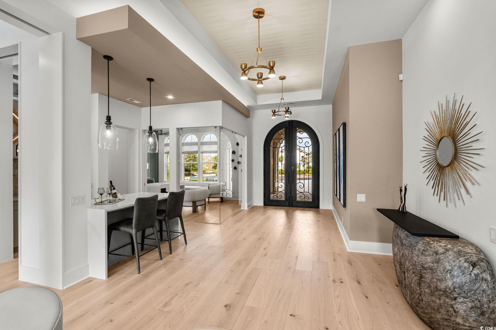 9273 Venezia Circle Myrtle Beach, SC 29579 - Photo 17 of 40 Foyer entrance with a chandelier, french doors, light wood-type flooring, arched walkways, and a raised ceiling