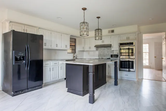 a kitchen with stainless steel appliances granite countertop a refrigerator a stove and a sink