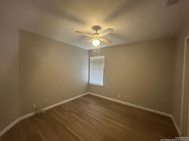 an empty room with a window and a ceiling fan