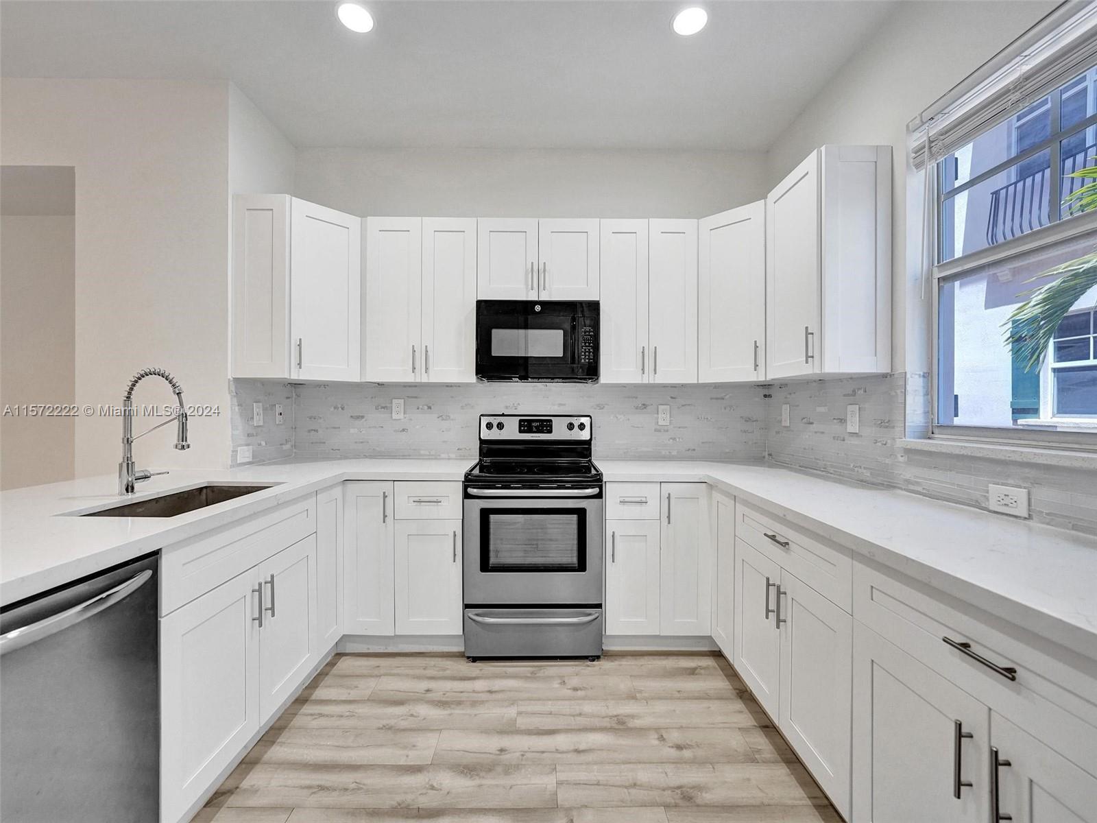 a kitchen with stainless steel appliances granite countertop a stove top oven a sink and dishwasher with white cabinets