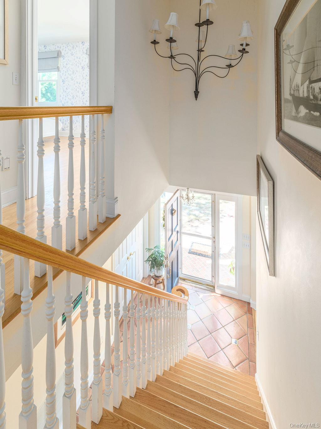 10947 North Bayview Road Southold, NY 11971 - Photo 29 of 43 Staircase featuring a chandelier and wood finished floors