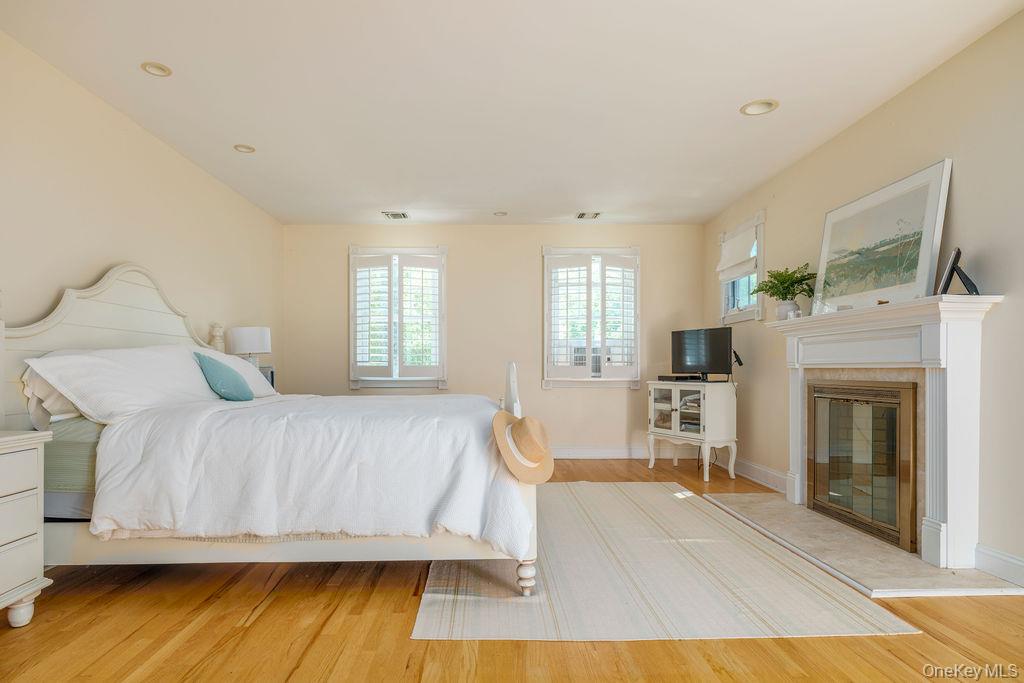 10947 North Bayview Road Southold, NY 11971 - Photo 30 of 43 Bedroom featuring wood finished floors, a glass covered fireplace, and recessed lighting