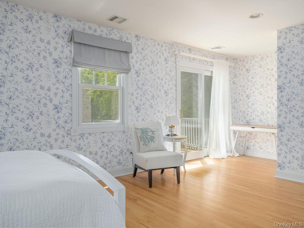 10947 North Bayview Road Southold, NY 11971 - Photo 35 of 43 Bedroom with light wood finished floors, multiple windows, access to outside, and wallpapered walls