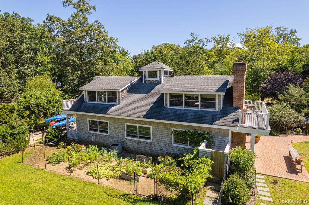 10947 North Bayview Road Southold, NY 11971 - Photo 8 of 43 View of front of property featuring a balcony, a gate, a vegetable garden, roof with shingles, and a chimney