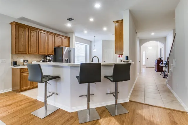 a kitchen with stainless steel appliances kitchen island granite countertop a stove a refrigerator a sink and white cabinets with wooden floor