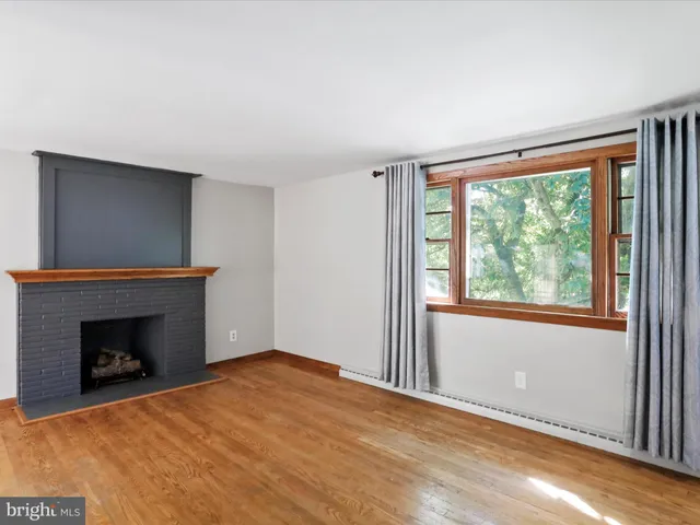 a view of empty room with wooden floor and fireplace
